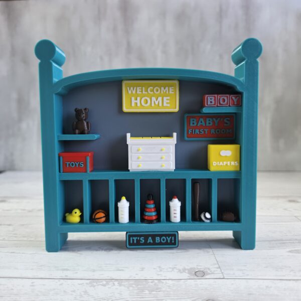20261020_153121 Crib-shaped nursery shadow box in teal and misty blue with red, yellow, and white miniatures, front view