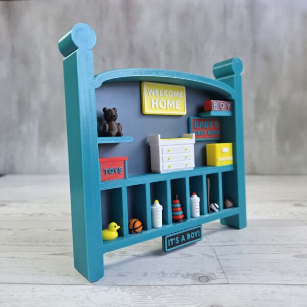 20261020_153136 Crib-shaped nursery shadow box in teal and misty blue with red, yellow, and white miniatures, right angle view