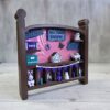 20261020_153246 Crib-shaped nursery shadow box in brown and pink with purple, teal, and white miniatures, right angle view